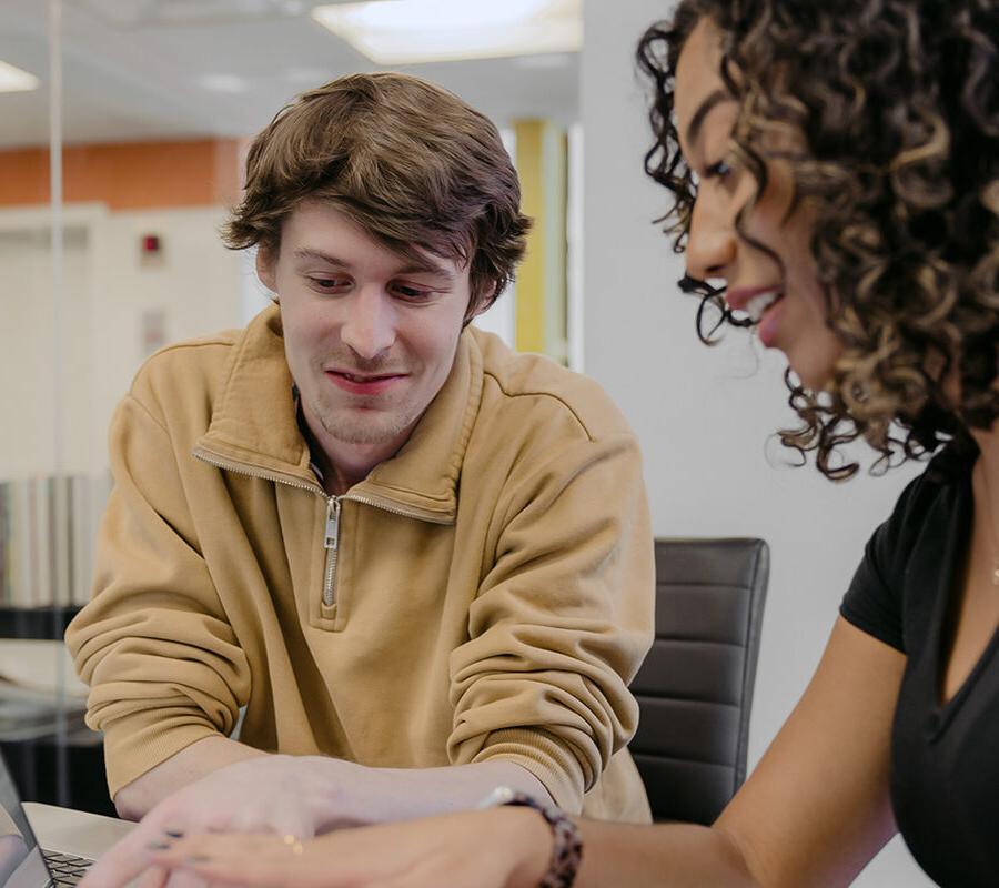 Two business administration students study together at a laptop